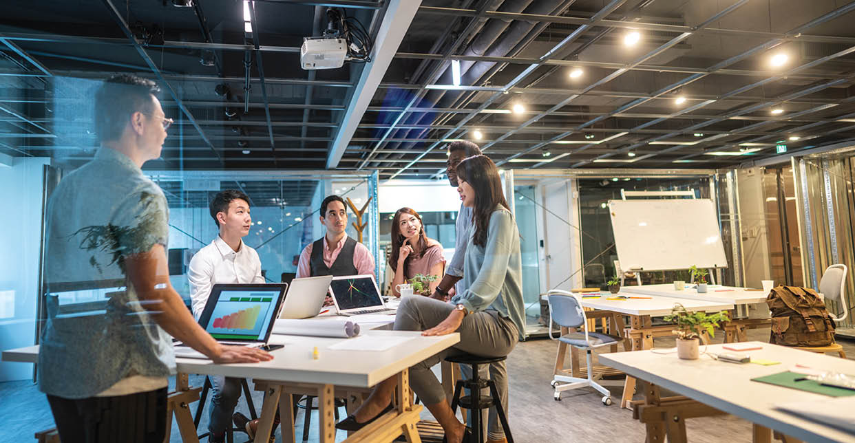 Group of young, modern people sitting on business meeting in modern coworking space and suggesting ideas for the best business strategy