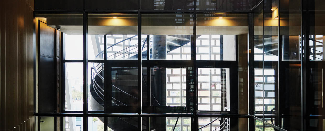 Wide shot of smiling businessmen in discussion in glass hallway of hotel during business trip